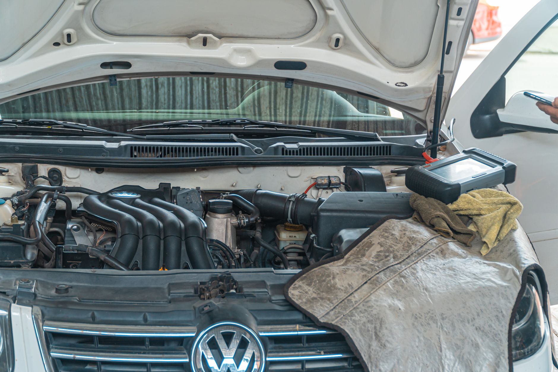 Acercamiento de un motor de coche Volkswagen en reparación en un garaje, con herramientas y equipos de diagnóstico en uso.